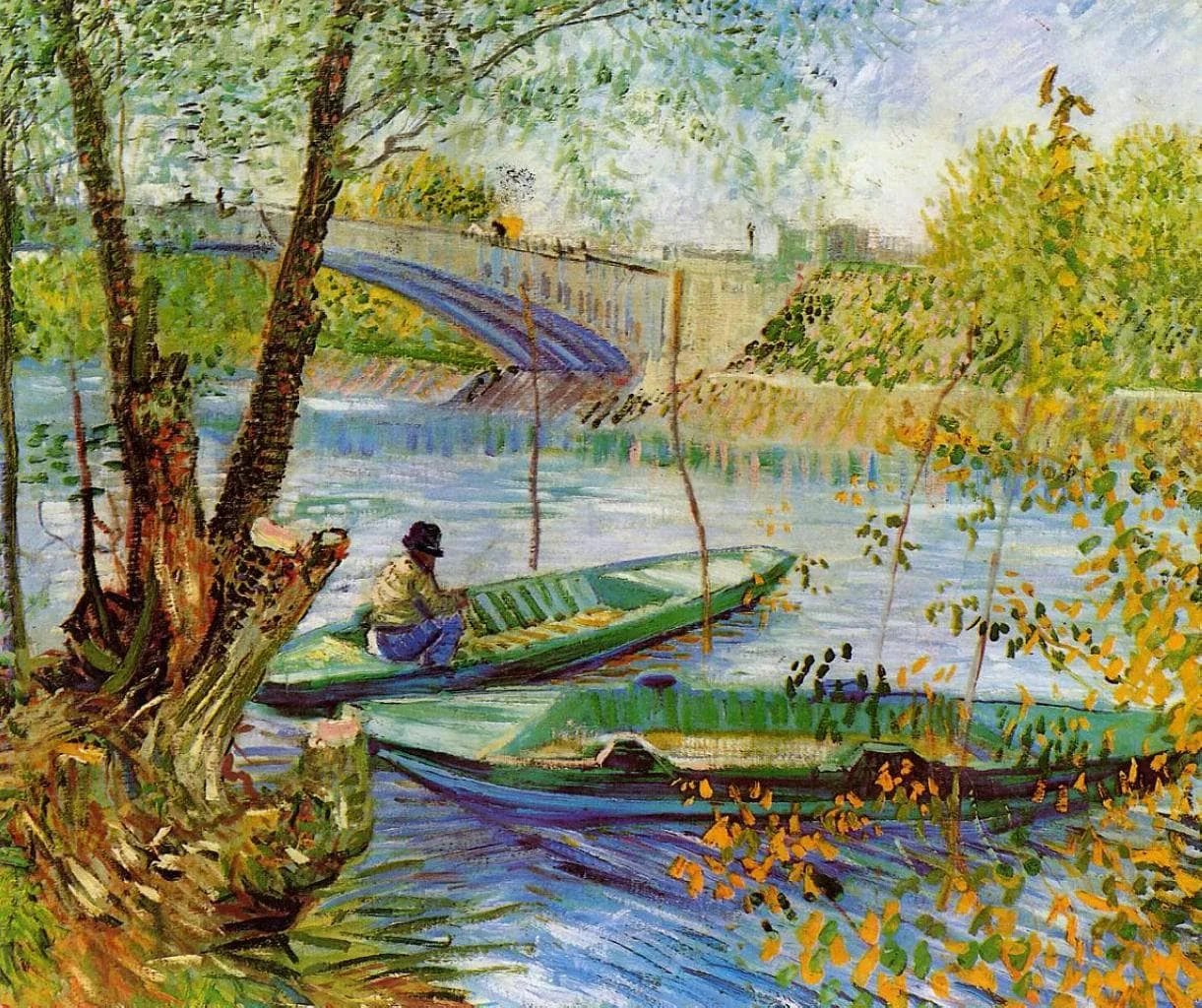 A fisherman sits in a flat-bottomed boat beside a willow-lined bank, with a second boat in the water and a bridge crossing the river behind in spring light.