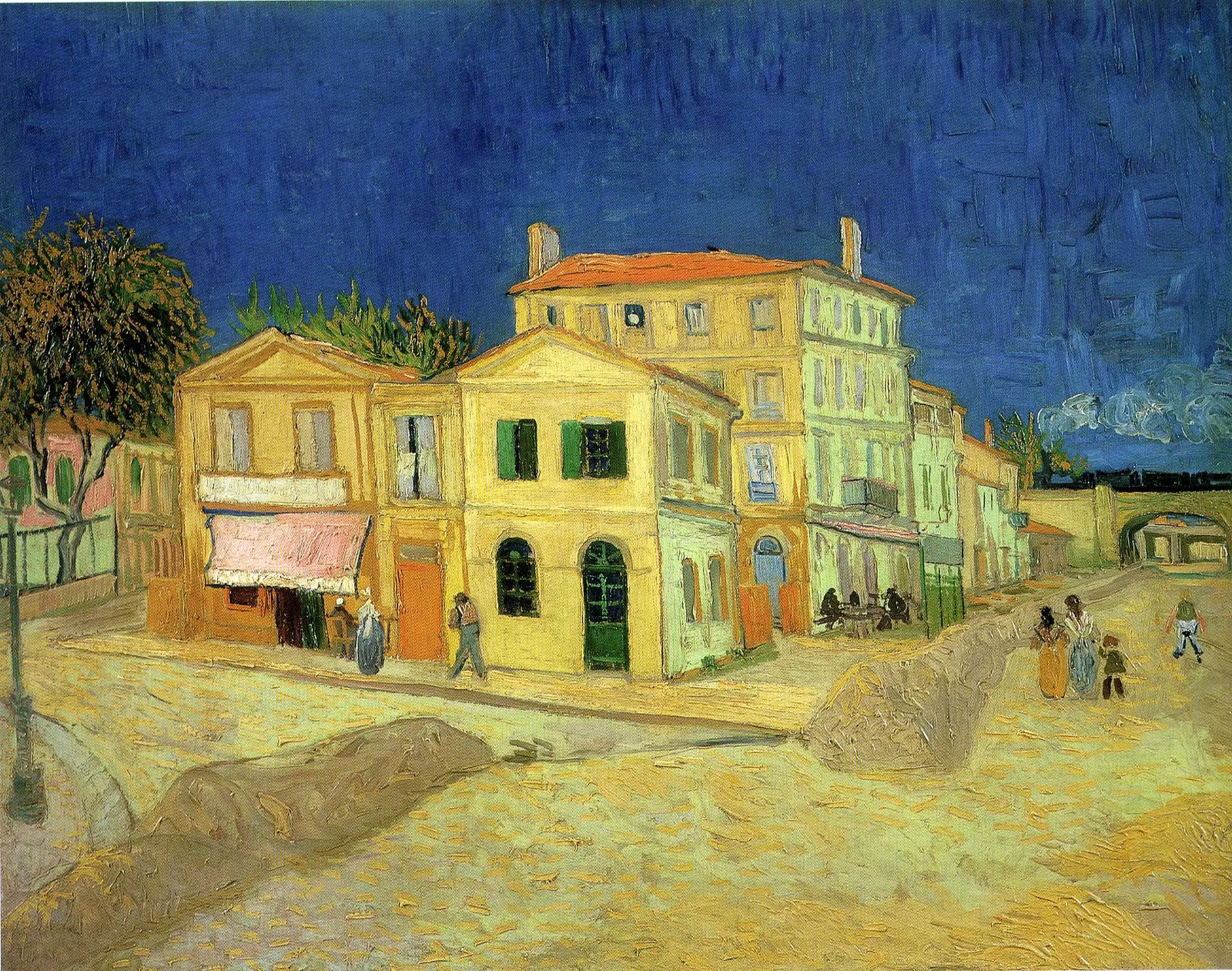 A yellow corner building with green shutters stands on a sunlit square under a deep blue sky; a pink-roofed house rises behind it, a railway bridge crosses the street at right and small figures walk along the pavement.